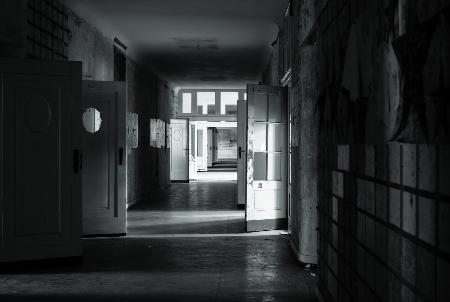 Empty hallway with peeling paint and many open doors.